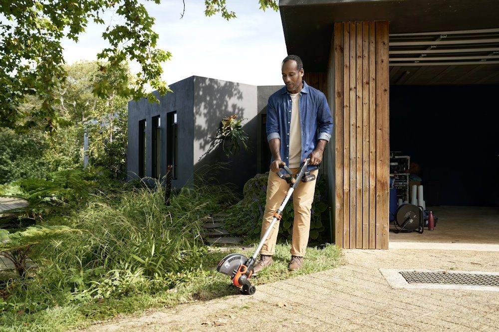 Person trimmt Rasenkante mit Rasentrimmer